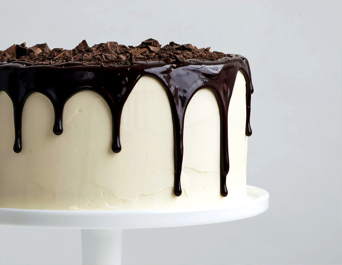 Frosted cake with dark chocolate ganache drip and chopped chocolate on top