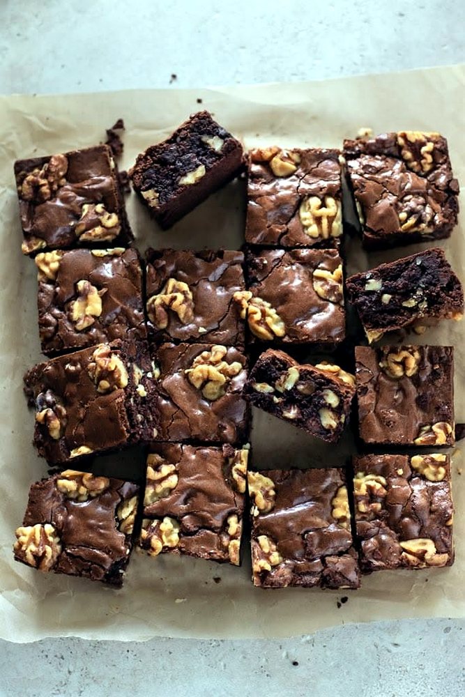 Walnut-topped fudge brownie squares on parchment paper